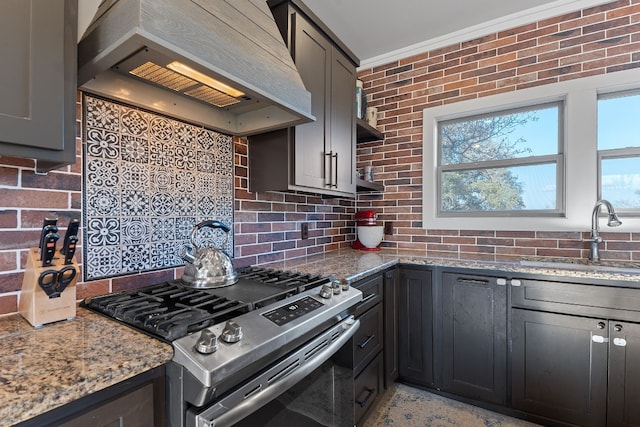 kitchen featuring sink, tasteful backsplash, light stone countertops, custom range hood, and gas stove