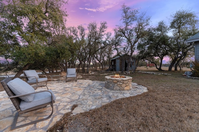 patio terrace at dusk featuring an outdoor fire pit and an outdoor structure