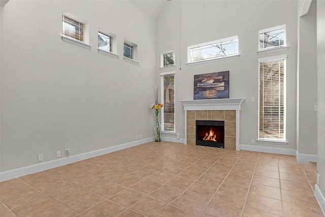 unfurnished living room with a high ceiling, a tile fireplace, and light tile patterned floors