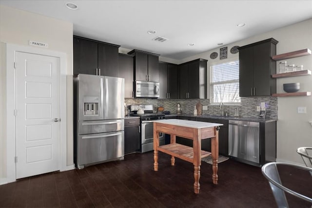 kitchen with appliances with stainless steel finishes, sink, tasteful backsplash, and dark hardwood / wood-style floors