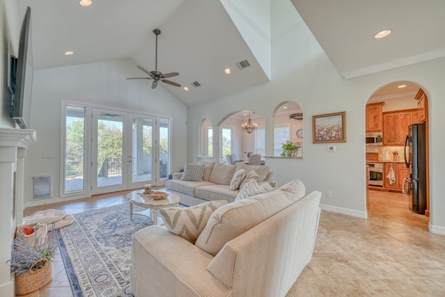 living room with light tile patterned flooring, ceiling fan with notable chandelier, and high vaulted ceiling