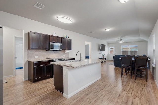 kitchen with stainless steel appliances, sink, a center island with sink, and light hardwood / wood-style flooring