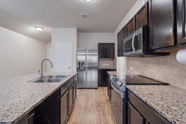 kitchen featuring sink, light hardwood / wood-style flooring, stainless steel appliances, dark brown cabinetry, and decorative backsplash