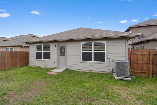 rear view of property with central AC unit and a lawn