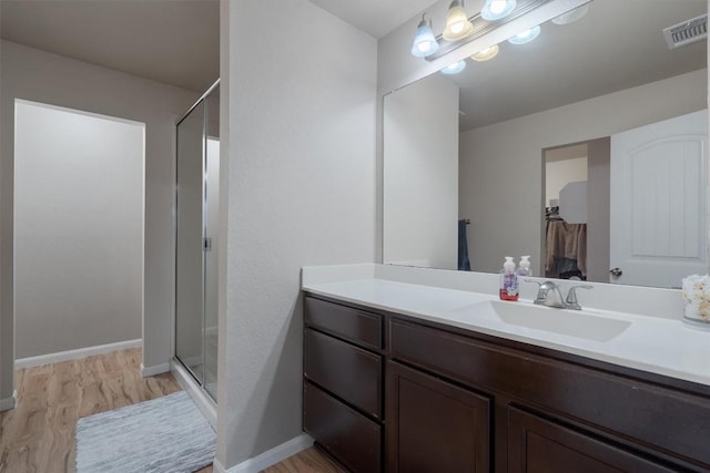 bathroom with a shower with door, vanity, and hardwood / wood-style floors