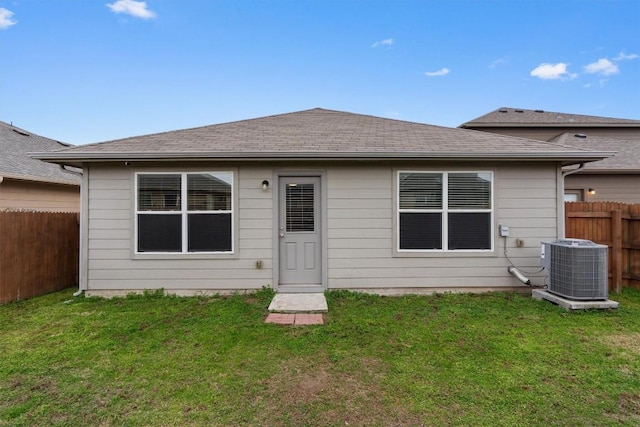 rear view of property with cooling unit and a yard