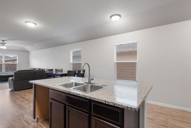 kitchen featuring dark brown cabinetry, light hardwood / wood-style floors, sink, and a center island with sink