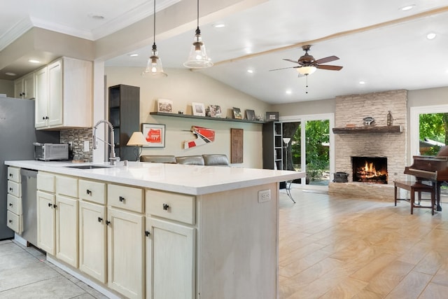 kitchen featuring a stone fireplace, dishwasher, sink, decorative backsplash, and hanging light fixtures