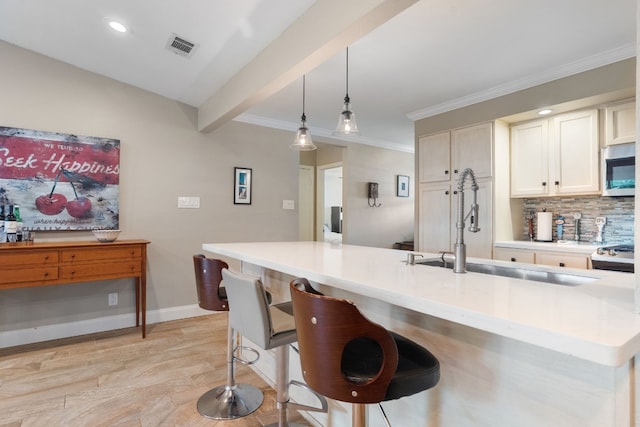 kitchen featuring sink, a breakfast bar area, decorative light fixtures, beamed ceiling, and backsplash