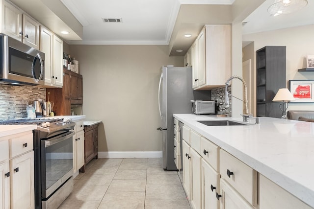 kitchen with light tile patterned flooring, sink, backsplash, ornamental molding, and stainless steel appliances