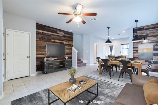 living room featuring wooden walls, ceiling fan, and light tile patterned flooring