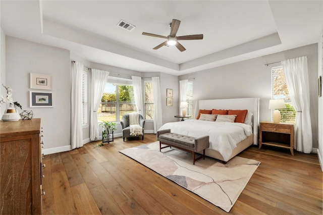 208 Wester Ross Ln, Austin, TX 78738 - bedroom featuring visible vents, a raised ceiling, light wood-style floors, and multiple windows