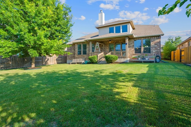 rear view of house featuring a yard and covered porch