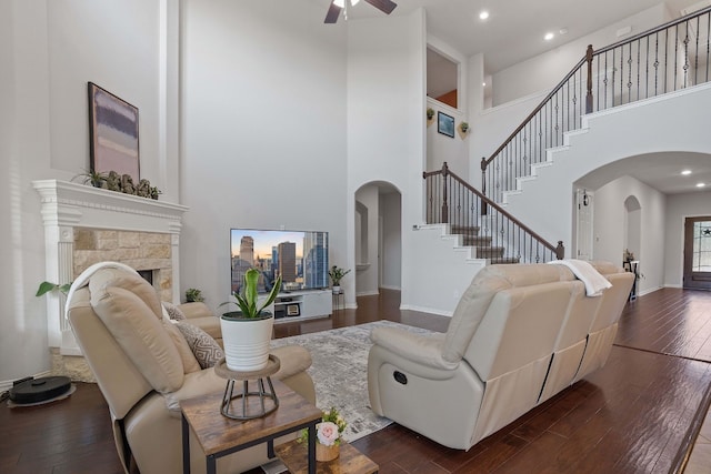 living room featuring a high ceiling, dark hardwood / wood-style flooring, ceiling fan, and a fireplace