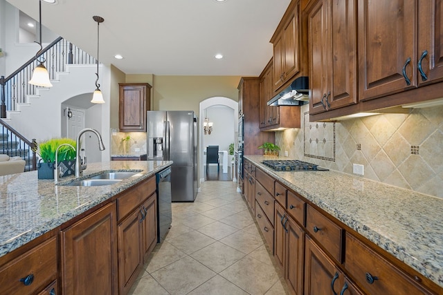 kitchen featuring pendant lighting, sink, exhaust hood, light stone counters, and black appliances