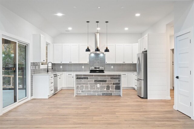 kitchen with wall chimney exhaust hood, light wood finished floors, appliances with stainless steel finishes, and a kitchen island