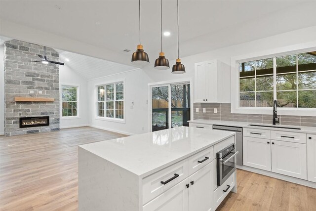 kitchen with lofted ceiling, a sink, light wood-style floors, appliances with stainless steel finishes, and backsplash