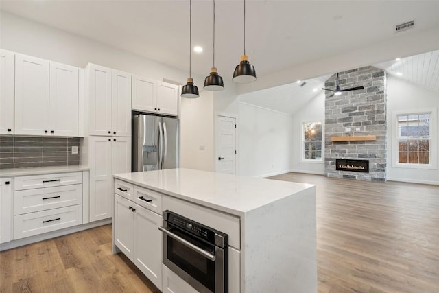 kitchen featuring light countertops, lofted ceiling, stainless steel appliances, light wood-style floors, and white cabinetry