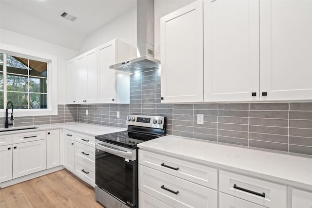 kitchen with visible vents, a sink, stainless steel range with electric cooktop, wall chimney range hood, and tasteful backsplash