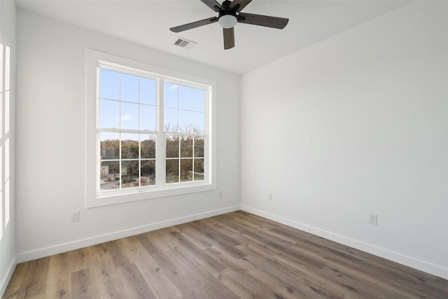 spare room with ceiling fan, wood finished floors, visible vents, and baseboards