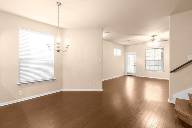 spare room with ceiling fan with notable chandelier and dark hardwood / wood-style flooring