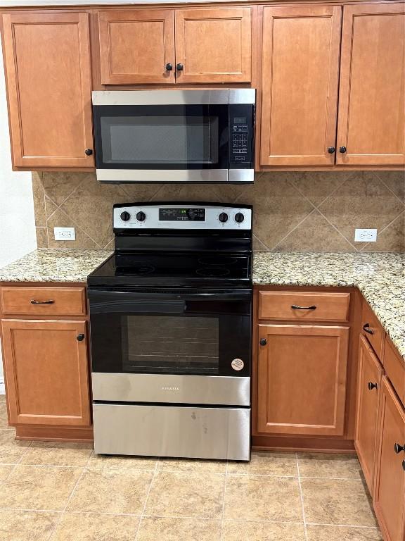 kitchen featuring light stone counters, tasteful backsplash, and stainless steel appliances