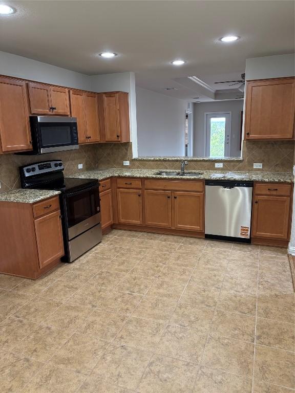 kitchen featuring light stone counters, sink, decorative backsplash, and appliances with stainless steel finishes