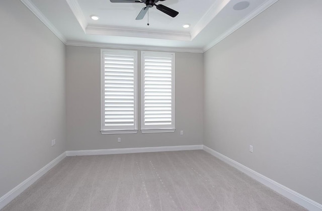 carpeted spare room with crown molding, ceiling fan, and a raised ceiling