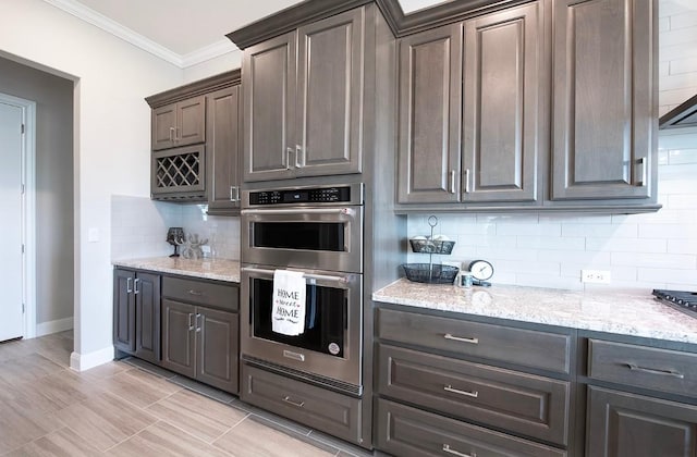 kitchen featuring tasteful backsplash, ornamental molding, light stone counters, dark brown cabinets, and stainless steel double oven