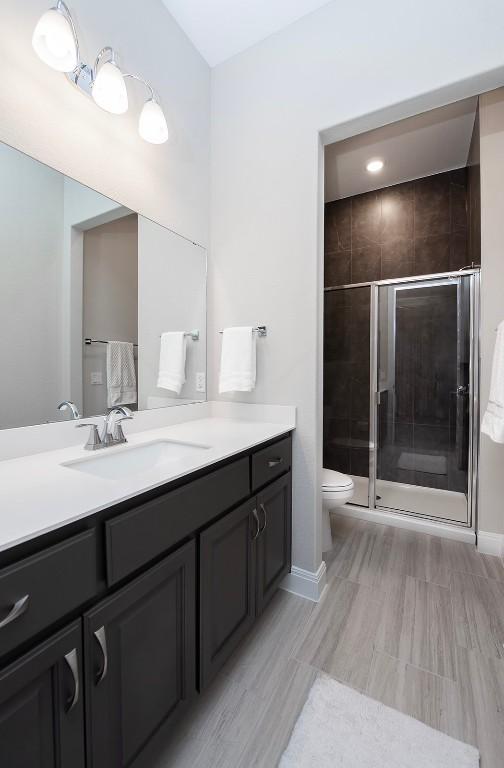 bathroom with vanity, a shower with shower door, and toilet