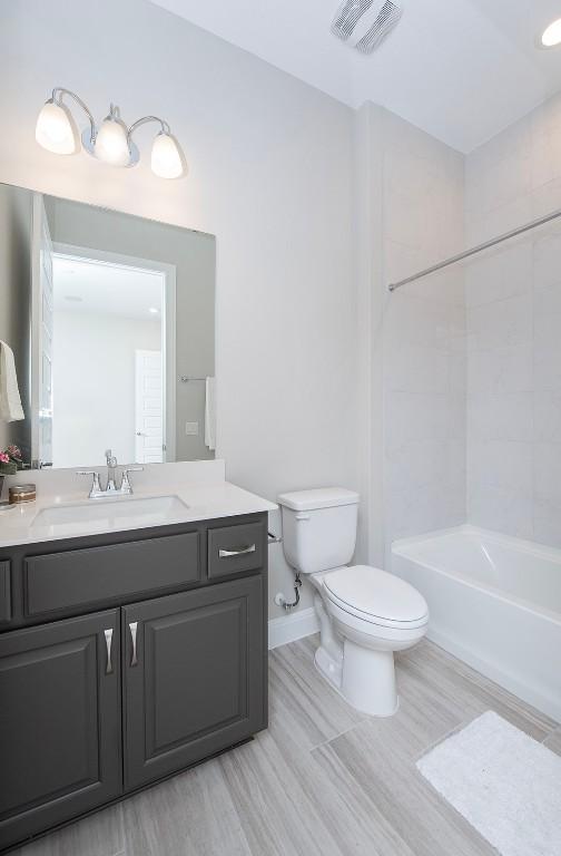 full bathroom with vanity, tiled shower / bath, and toilet