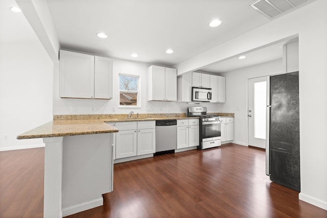 kitchen featuring sink, appliances with stainless steel finishes, dark hardwood / wood-style floors, kitchen peninsula, and white cabinets