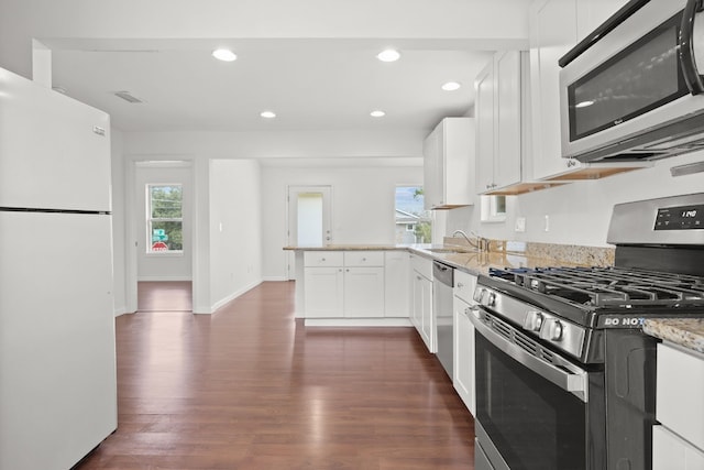 kitchen with dark wood-type flooring, sink, white cabinetry, light stone counters, and stainless steel appliances