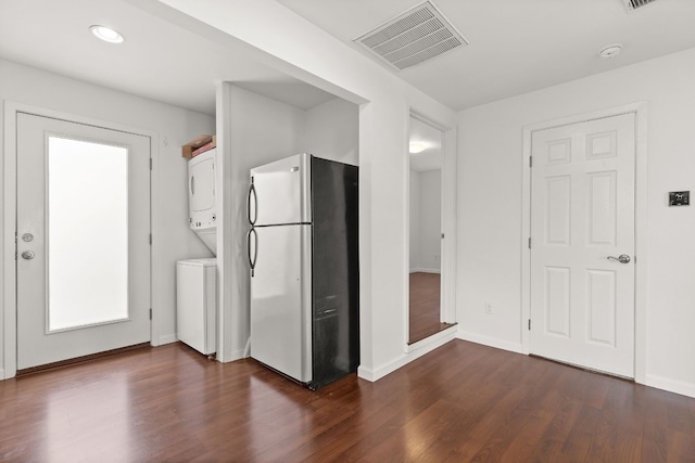 kitchen featuring dark hardwood / wood-style flooring, stainless steel refrigerator, and stacked washer / dryer