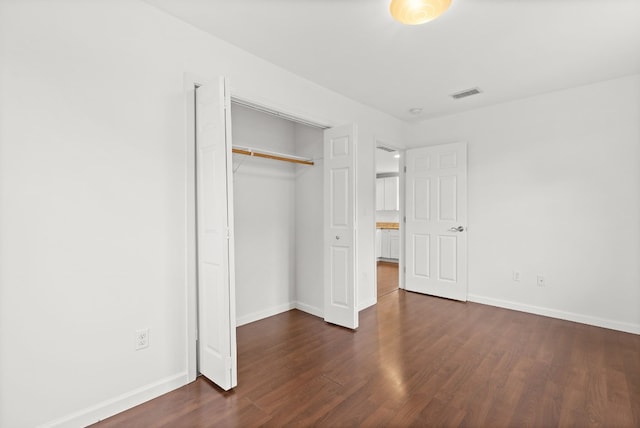 unfurnished bedroom featuring dark wood-type flooring and a closet