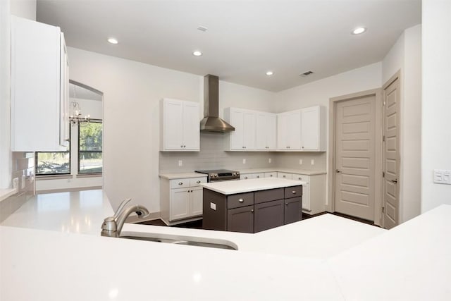 kitchen with sink, white cabinets, a center island, wall chimney exhaust hood, and stainless steel electric range