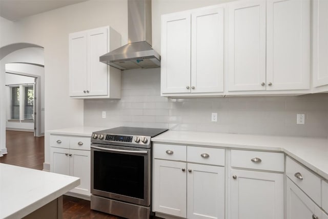 kitchen featuring white cabinets, decorative backsplash, wall chimney exhaust hood, and stainless steel electric range oven