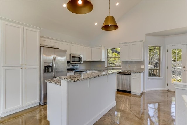 kitchen with stainless steel appliances, white cabinetry, and light stone counters