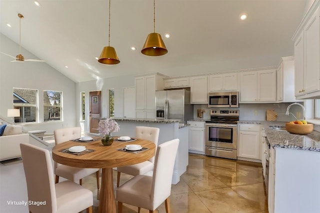 kitchen with sink, light stone counters, white cabinetry, a center island, and appliances with stainless steel finishes