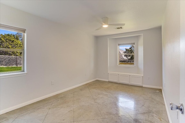 unfurnished room featuring a healthy amount of sunlight, light tile patterned floors, and ceiling fan