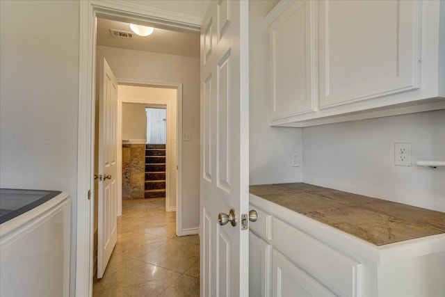 interior space with light tile patterned floors and white cabinets