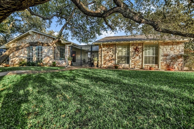 ranch-style house featuring a front yard, stone siding, and glass enclosure