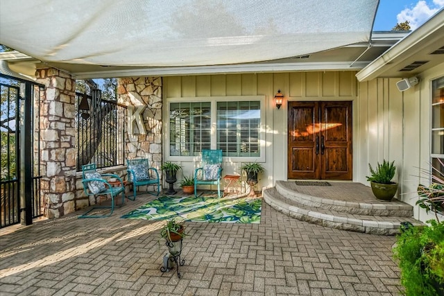 entrance to property featuring stone siding, board and batten siding, and visible vents