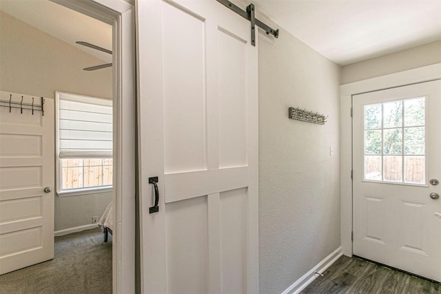 entryway with dark wood-type flooring, ceiling fan, a healthy amount of sunlight, and a barn door