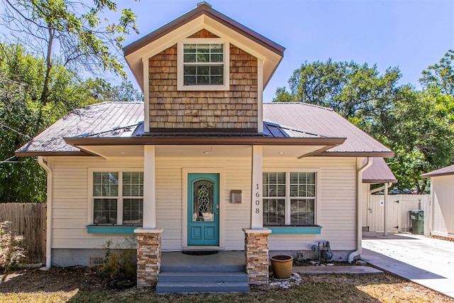 view of front of home featuring metal roof, a porch, and fence