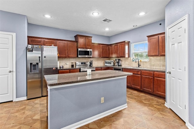 kitchen with sink, backsplash, a center island, and appliances with stainless steel finishes