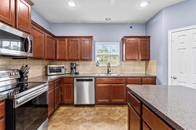 kitchen with sink, backsplash, a textured ceiling, and appliances with stainless steel finishes