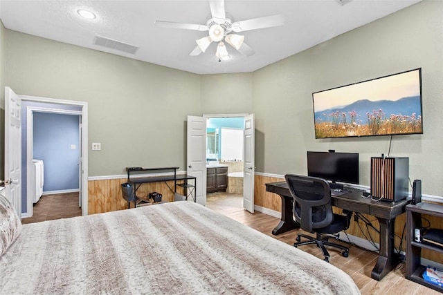 bedroom with connected bathroom, light hardwood / wood-style flooring, washer / clothes dryer, and ceiling fan