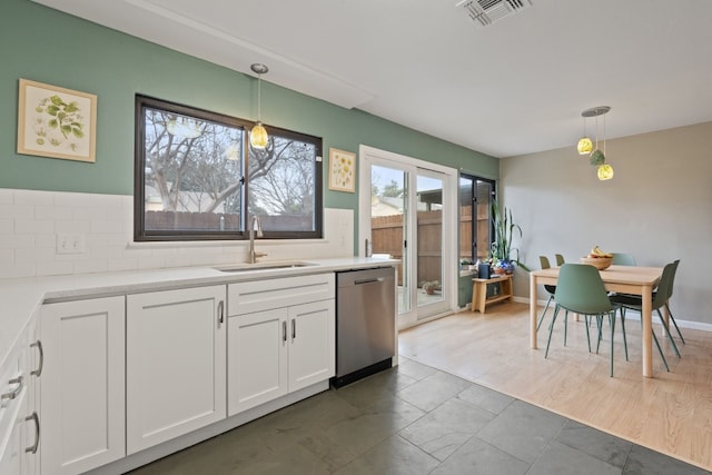 kitchen featuring hanging light fixtures, dishwasher, sink, and white cabinetry