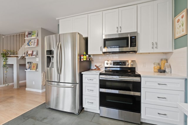 kitchen featuring stainless steel appliances, white cabinetry, hardwood / wood-style floors, and backsplash